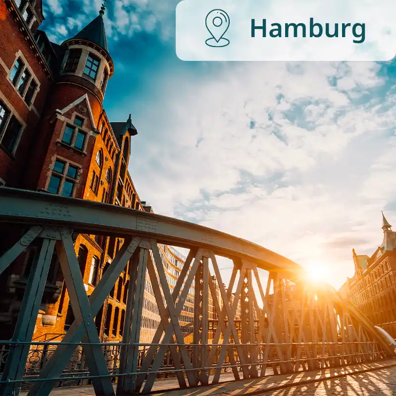 Backsteingebäude und Metallbrücke in Hamburg bei tief stehender Sonne.