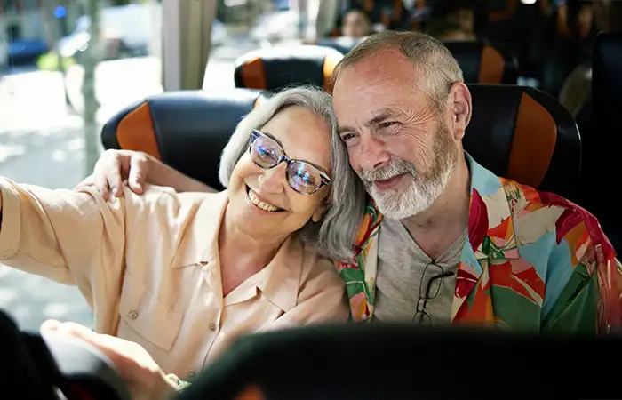 Seniorin und Senior machen fröhlich ein Selfie im Reisebus.