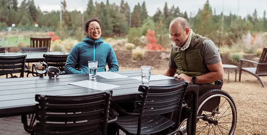Gesprächsszene im Außenbereich mit barrierefreiem Sitzplatz.