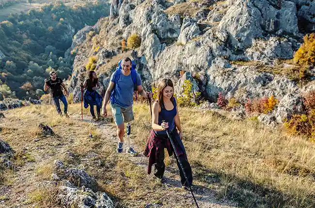 Gruppe wandert auf felsigem Pfad, ein Mann hat eine Beinprothese.