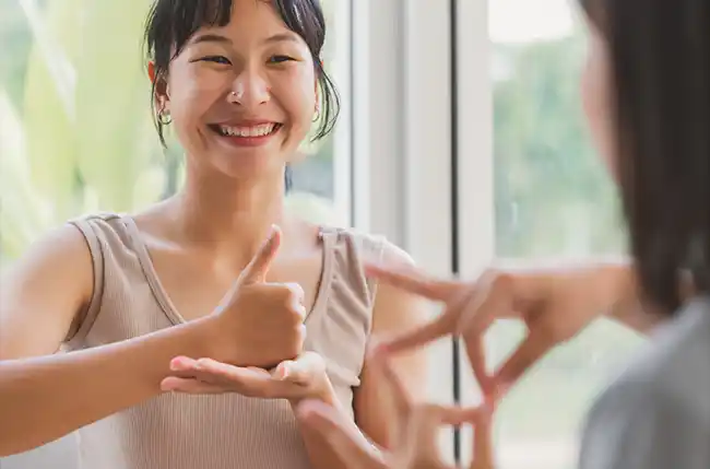 Zwei Frauen unterhalten sich lächelnd in Gebärdensprache.